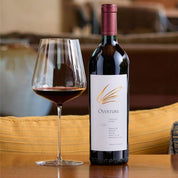 Bottle of Overture wine with a glass on a wooden table