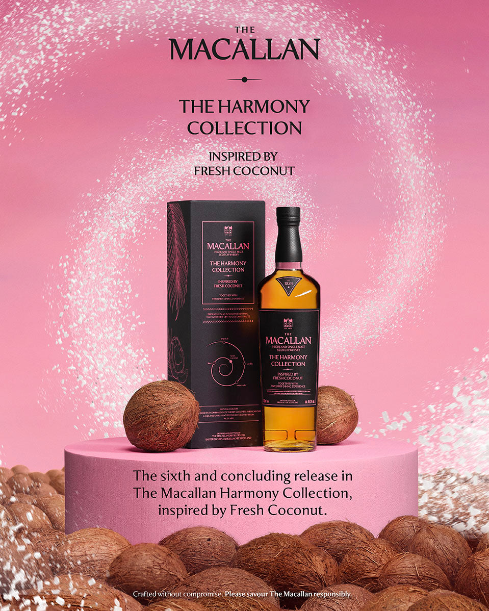 A bottle of The Macallan The Harmony Collection whisky stands next to its black box on a pink pedestal, surrounded by whole coconuts against a pink background with white splash details and product text.