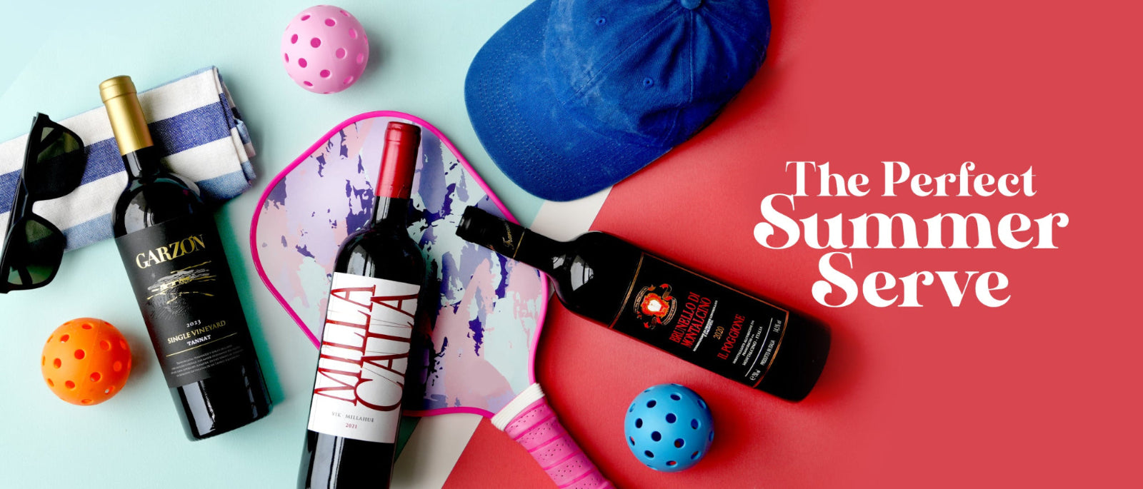 A styled flat-lay featuring two bottles of red wine, a blue baseball cap, colorful balls, sunglasses, and a tennis racket on a split light blue and coral background, with the text 'The Perfect Summer Serve' on the right.