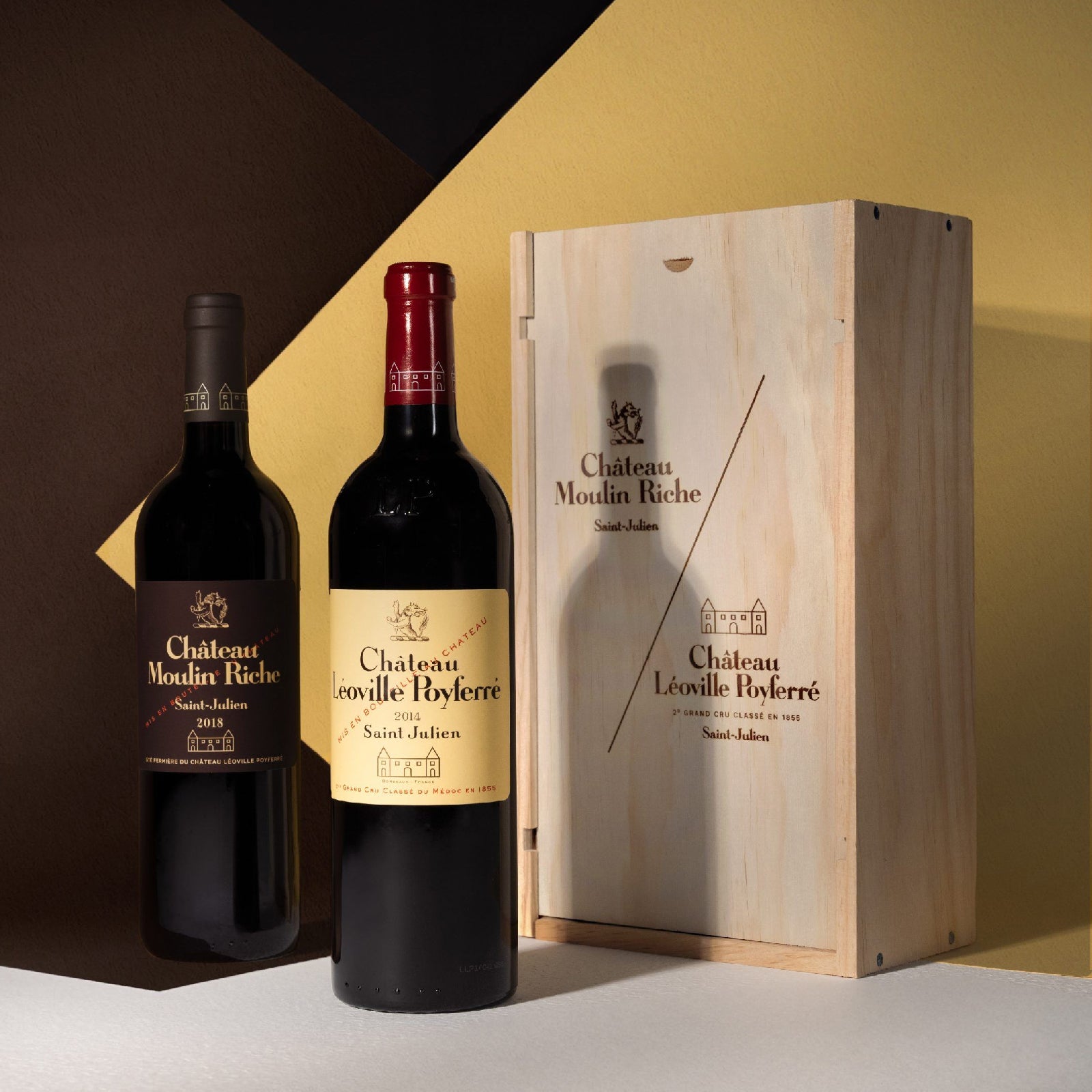 Two bottles of Chateau Moulins Riches wine with a wooden gift box on a gradient background