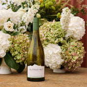 Green wine bottle with 'Cloudy Bay' label in front of hydrangea flowers