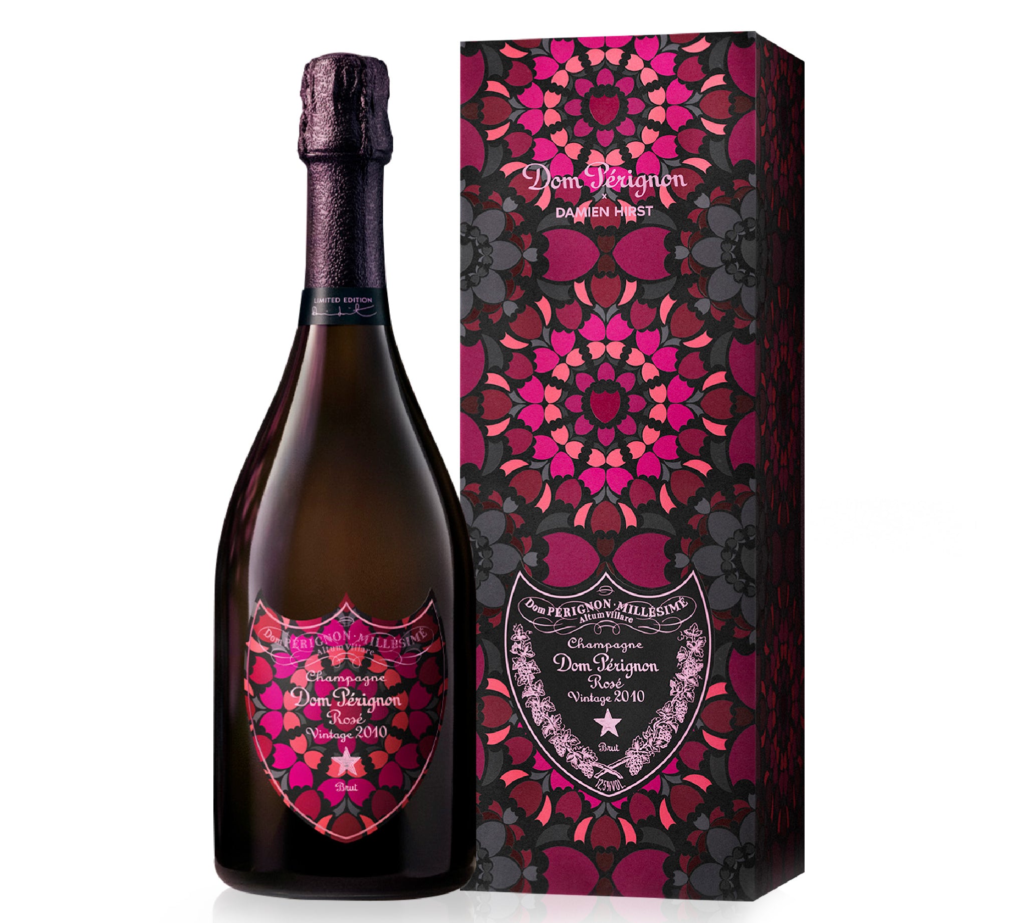 A bottle of Dom Pérignon Grand Cru Champagne next to its matching decorative packaging box, both featuring a vibrant magenta, pink, and dark red mandala pattern on a black background.