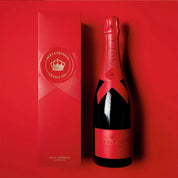 A bottle of Moët & Chandon Brut Impérial Champagne with its matching red gift box, set against a solid red background.