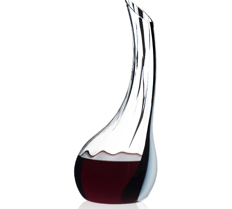 A Riedel handcrafted decanter made of optical blown glass with a black-white-black ornamental line, filled with red wine.