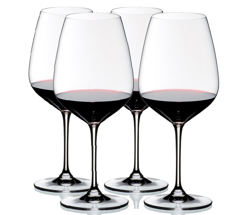 A set of four clear crystal wine glasses with a diamond-shaped bowl, long stems, and circular bases, filled with red wine.