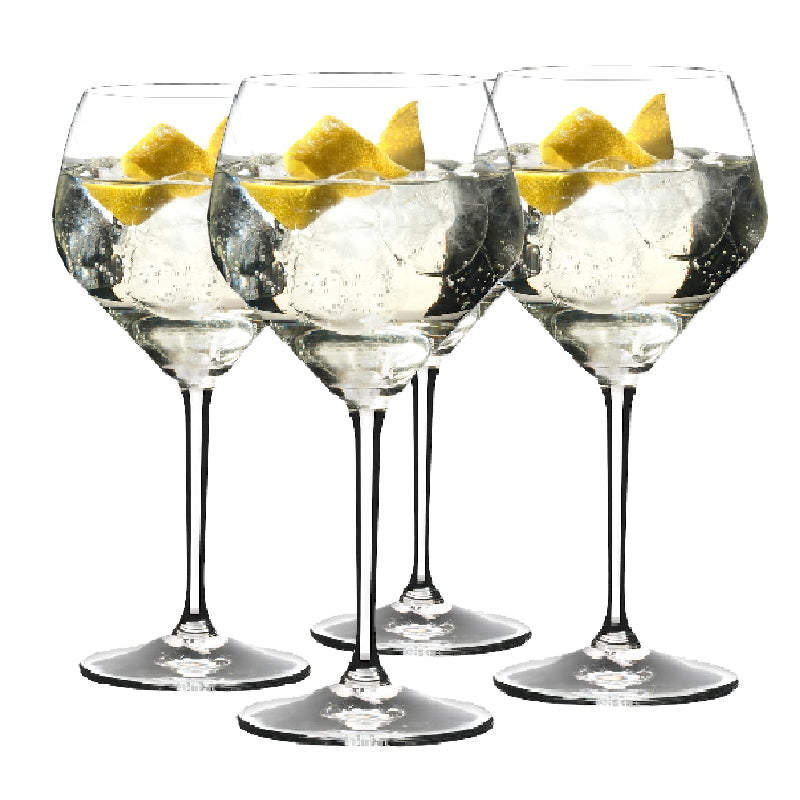 A set of four Riedel glasses with a tulip-shaped design, filled with water and a slice of lemon, showcasing their large bowls and slender stems.