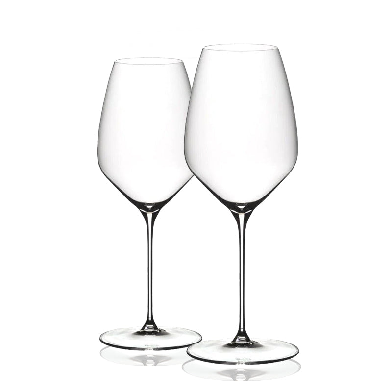 A set of two clear Riedel glasses with a tall and slender stem design, standing upright.