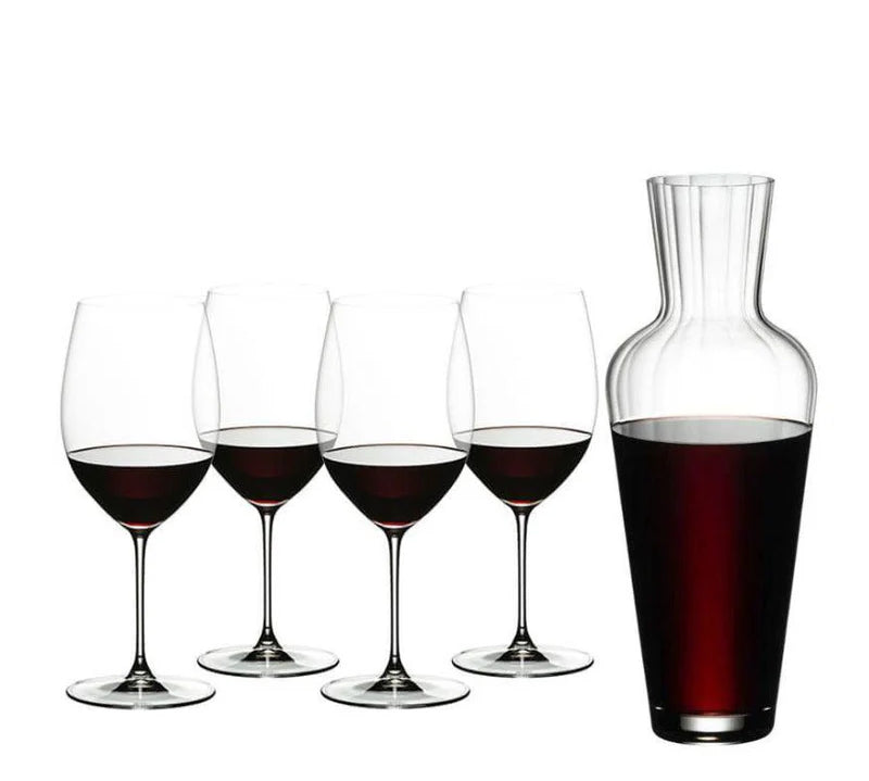 Set of wine glasses with red wine and a decanter also filled with red wine on a white background