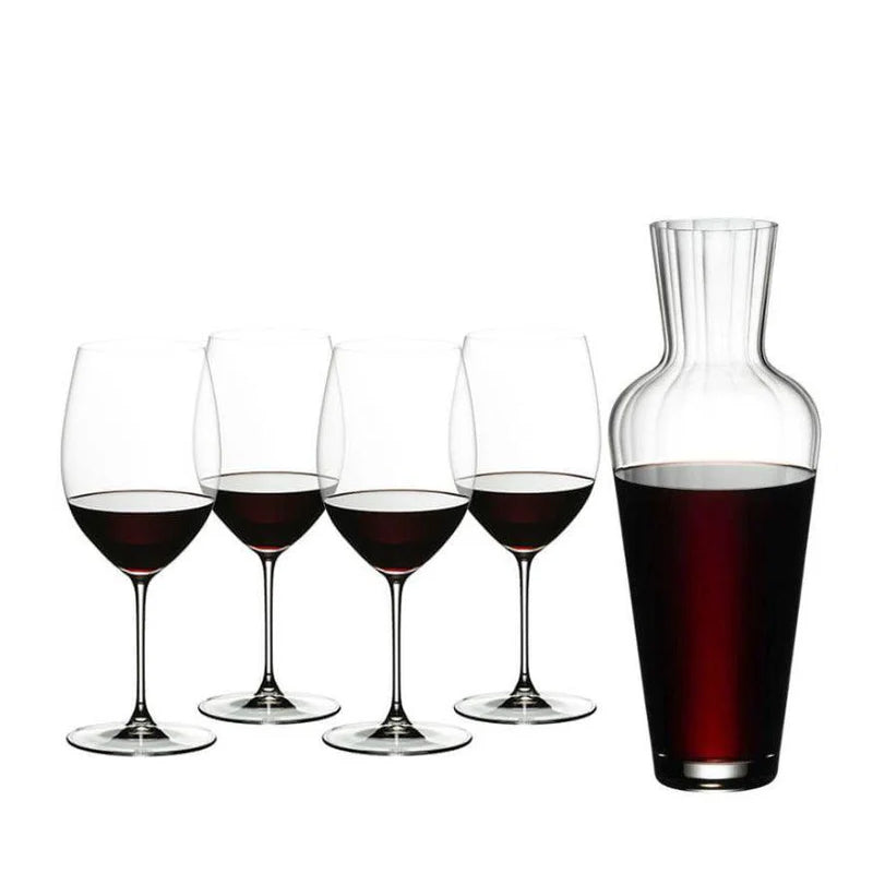 Set of wine glasses with red wine and a decanter also filled with red wine on a white background